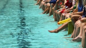 Many people sitting on the side of a pool. Contact a Texas drowning accident attorney if a loved one suffered an accident at a pool or lake.