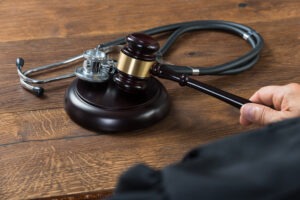 Cropped,image,of,judge,hitting,gavel,with,stethoscope,in,courtroom